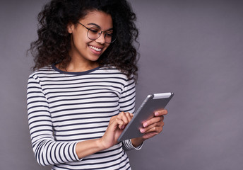 Fototapeta premium Beautiful young african woman is using a tablet.
