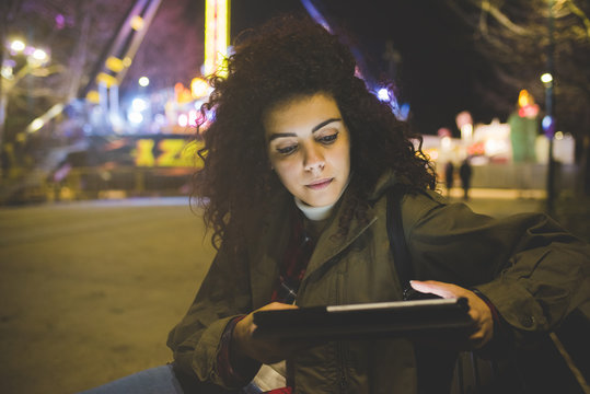 Young beautiful mixed race woman outdoor evening using tablet