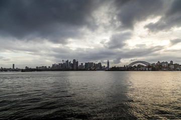 Fototapeta premium Sydney in Australia, the skyline with the Opera house and the Harbour Bridge during a cloudy but warm day.
