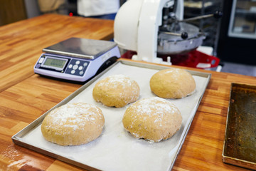 loaves of baked white bread lie on a baking sheet on baking paper next to the scales