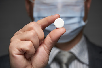 a man with a mask on his face for antivirus individual protection showing a pill - healthcare and medicine concept, prevention tips