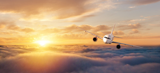 Fototapeta premium Samolot komercyjny lecący nad dramatycznym zachodem słońca