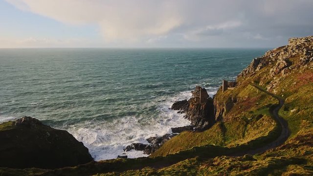 Botallack Tin Mines on seashore cliffs in Cornwall, England, with ocean landscape, on sunny evening