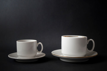 Different white cups for coffee on a black background.