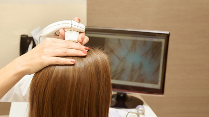 Woman check head hair in clinic. Doctor hand hold medical equipment. increased image on computer...