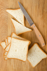 Top view of wooden cutting board, white bread for toasts, whife on it.Preparing tasty toasts