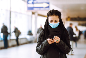 Girl in protective sterile medical mask on her face with a phone in  quarantine city. Woman using the phone to search for news. The concept of preventing the spread of the epidemic. 