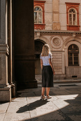 Fototapeta na wymiar A beautiful woman with blond hair walks through the streets of the city. Girl enjoy holidays in Europe. Beautiful historical architecture. Italian weekend. Travel to Turin, Italy. Adventure lifestyle