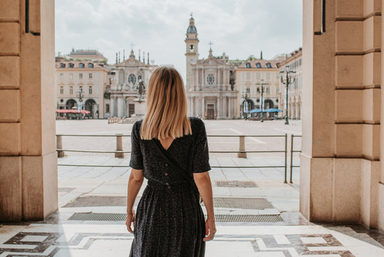 Fototapeta A beautiful woman with blond hair walks through the streets of the city. Girl enjoy holidays in Europe. Beautiful historical architecture. Italian weekend. Travel to Turin, Italy. Adventure lifestyle