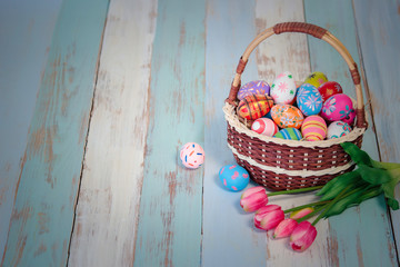 Easter eggs with tulip flowers on wooden table, colorful eggs in the basket as background, festival and holiday spring caming, Easter calibration