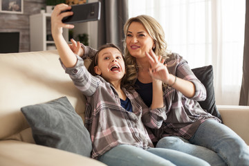 Funny little daughter and her mother are taking a selfie