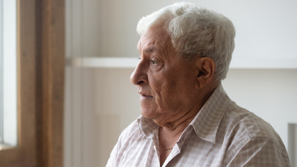 Fototapeta na wymiar Head shot close up serious pensive older man looking out window, thoughtful mature male with grey hair lost in thoughts or memories, thinking about problem, nostalgia and melancholy, mental disorder