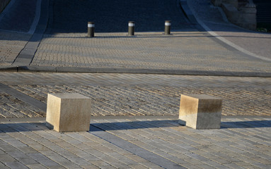 detail of beige-colored granite tiles laid in rows straight on it stands stone blocks as a...