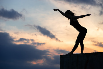 Young woman dancer on outdoor sunrise background. Concept of freedom, brave and happy lifestyle
