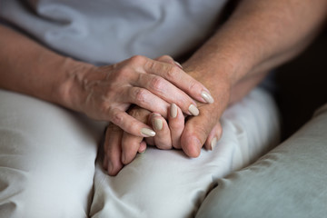 Close up middle-aged wife holding older husband hands, expressing love and empathy, caring adult daughter helping elderly father to overcome problems, caregiver consoling and supporting patient