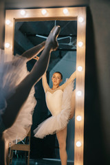 Elegant ballerina in white dress dancing in studio