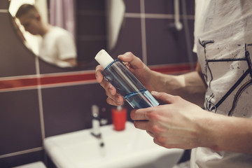 man with a bottle of liquid antibacterial soap in the bathroom . prevention of bacterial diseases and viruses