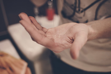 man squeezes antibacterial soap on his hand . protection from viruses and germs