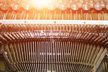 Mechanism of typesetting strikers with the English alphabet in an old retro typewriter.Solar glare.