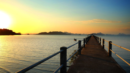 Concrete bridge to old port with sunset sky seascape background in fisherman village island in South of Thailand.