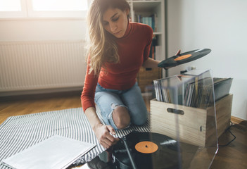 Young woman playing vinyl record on turntable. Playing music on turntable, leisure time, hobbie