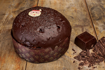 Traditional Italian Christmas cake from Milan: handmade panettone with chocolate glaze, components on view on rustic wooden table and decorations.