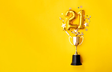 Number 21 gold anniversary celebration balloon exploding from a winning trophy - obrazy, fototapety, plakaty