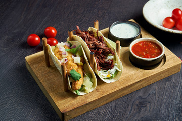 Appetizing Mexican tacos with fried chicken and stewed beef, cabbage, onions and parsley in special...