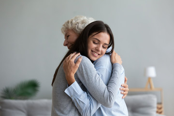 Happy mature mother and grown-up adult daughter hug cuddle share close intimate moment together, smiling elderly mom and millennial girl child embrace make peace reconcile after fight - obrazy, fototapety, plakaty