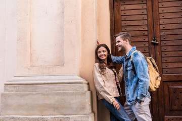 Boyfriend and girlfriend smiling near wall in city
