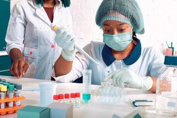 Female African medical students, young graduates in research laboratory or medical test lab perform...