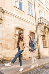 Fototapeta na wymiar Couple having fun while walking on sidewalk in city