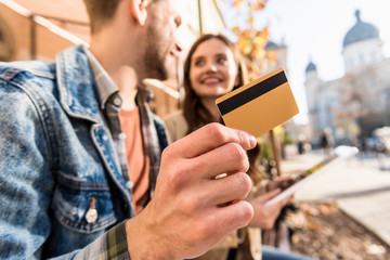 Cropped view of man with girl looking at each other, smiling and showing credit card