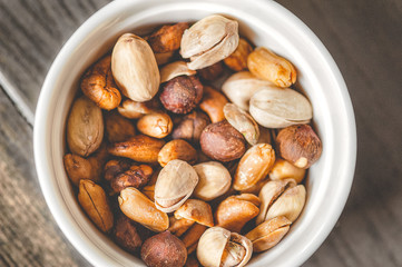 Mix of different nuts in a white bowl.