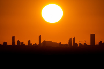 Sunset with big sun over Benidorm city skyline with text space