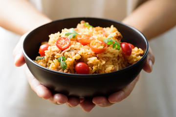 Fried rice with minced pork and tomato in a bowl holding by hand, Asian food