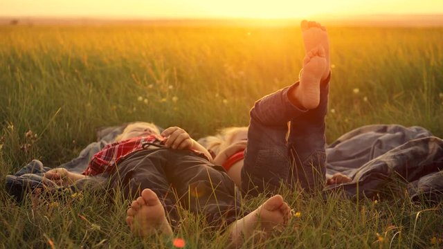 Two happy children, a boy and a girl, lie on the green grass on a summer day. Legs close up.