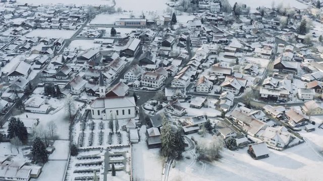 Aerial view of the small cozy german town at the mountain bottom at sunrise in a winter season, Halblech city, Germany, Bavaria, Branches of trees are covered with hoarfrost, sunny weather
