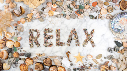 inscription relax with stones and shells lying on a marble background, composition of sea stones and seashells, word relax written by stones, relax word written with stones