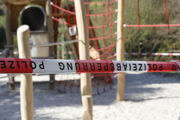 Leerer Spielplatz mit Polizeiabsperrung und Absperrband während covid-19 Coronavirus Epidemie