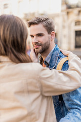 Partial view of boyfriend and girlfriend looking at each other and hugging in city