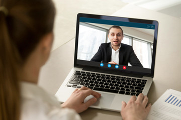Fototapeta na wymiar Back view of female employee talk with male businessman on webcam laptop conference, woman worker negotiate with man employer brainstorm on video call from home, online consultation concept