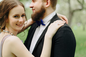 a young beautiful couple, a girl in a lilac dress and a man in black in a summer Park with Apple trees