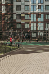 Fototapeta na wymiar Parents playing with kids in the yard of metropolis
