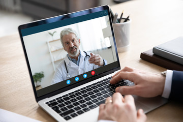 Fototapeta na wymiar Close up of male patient talk consult with doctor using video call on laptop, man speak discuss health problem with physician on webcam virtual conference from home, online consultation concept