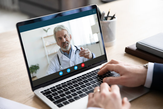 Close up of male patient talk consult with doctor using video call on laptop, man speak discuss health problem with physician on webcam virtual conference from home, online consultation concept