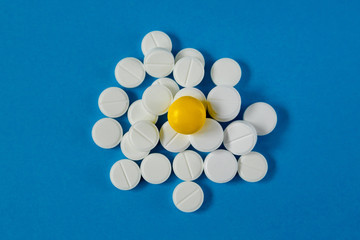heap of white pills and one red, on a blue background