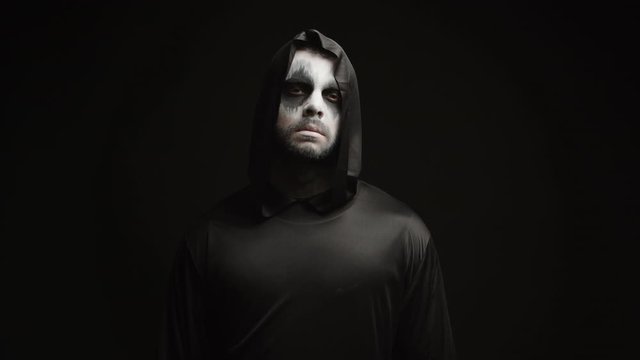 Young man dressed up like grim reaper over black background