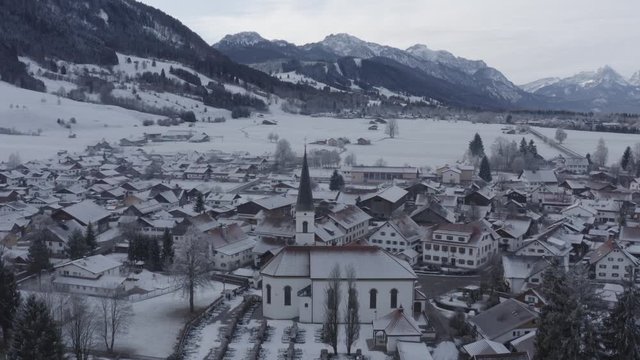 Aerial view of the small cozy german town at the mountain bottom at sunrise in a winter season, Halblech city, Germany, Bavaria, Branches of trees are covered with hoarfrost, sunny weather