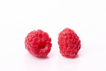 Two red juicy raspberries on a white background